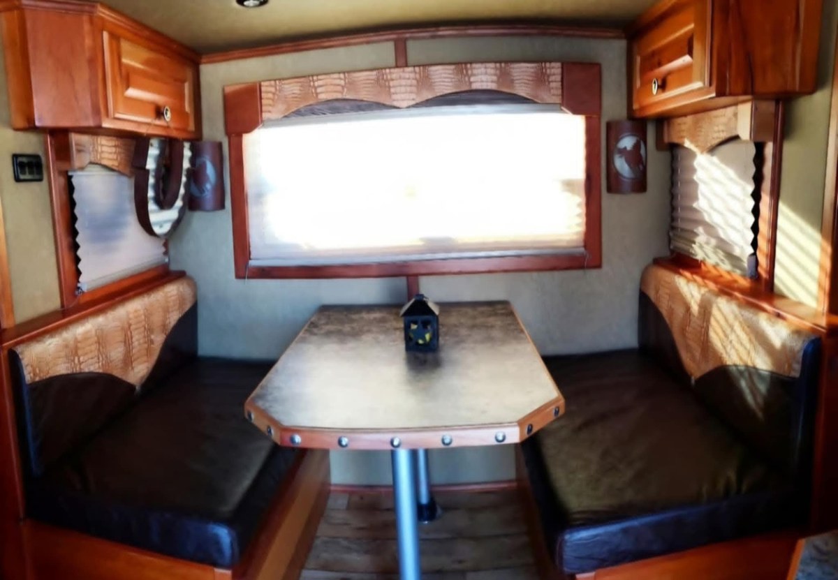 Inside the Cowgirl camper, with wooden cabinets and a dinette beneath a window