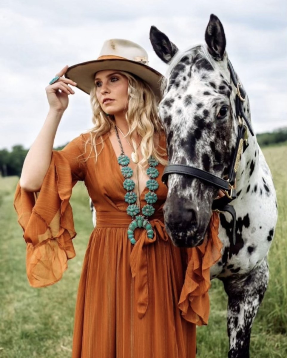 Emilya Washeleski in a western hat beside a spotted horse