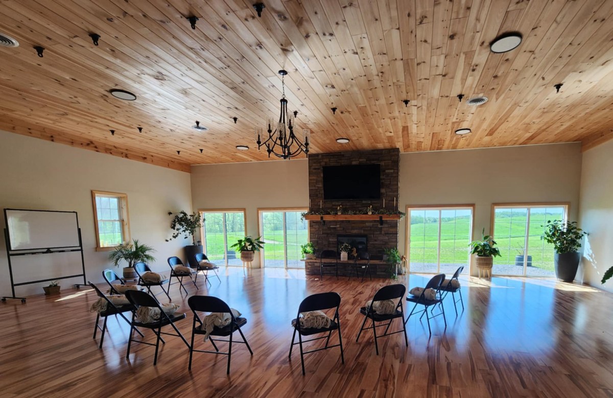 Fall Brook retreat center's wood-paneled yoga studio and dining area with a grand fireplace